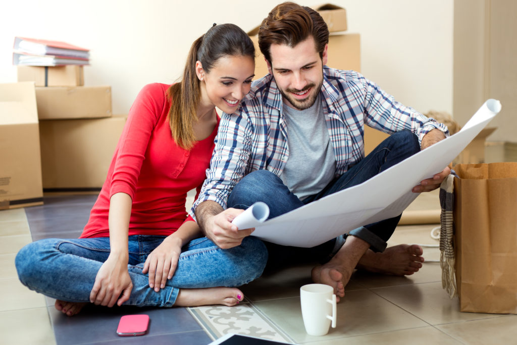 Buying Vs. Renting - Young couple looking at the blueprints of their new home